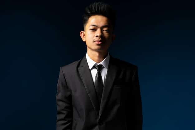 A medium shot of a well-known South Korean actor, dressed in a sleek black suit, holding a futuristic-looking pistol. He is positioned in what seems to be a high-tech command center. His expression is serious and focused, with a slight determined glint in his eyes. The background includes holographic screens displaying complex data visualizations and maps, which contribute to a sense of urgent high-stakes operation. The overall tone is professional and intense.