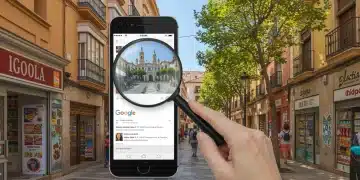 SEO local en España: Posiciona tu negocio en Google en 6 meses Fachada de negocios locales en una calle de España con un smartphone mostrando resultados de búsqueda de Google, simbolizando el SEO local.